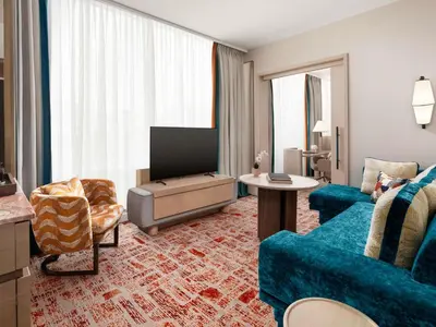 a living room with a blue couch and a television at Sofitel Montreal Golden Mile in Montréal