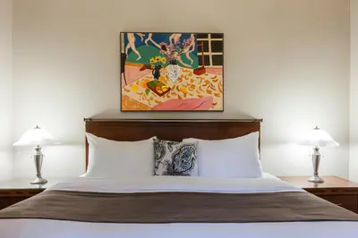 a bedroom with a bed with two lamps and a painting at Chateau Versailles in Montréal