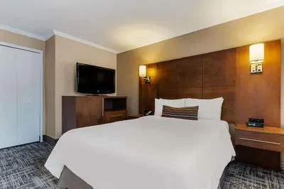 a bedroom with a white bed and a flat screen tv at Best Western Ville-Marie Montreal Hotel & Suites in Montréal