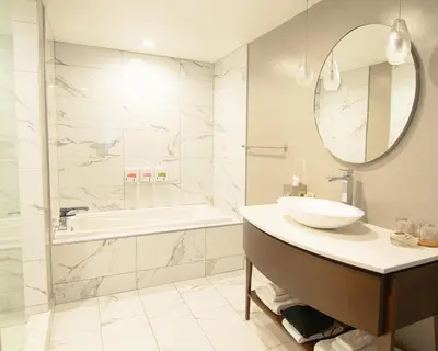a bathroom with a sink and a tub and a mirror at Hôtel Saint-Sulpice in Montréal