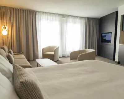 a hotel room with a large bed and chairs at Hôtel Saint-Sulpice in Montréal