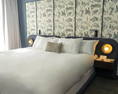 a bedroom with a large white bed with a large window at Hôtel Saint-Sulpice in Montréal