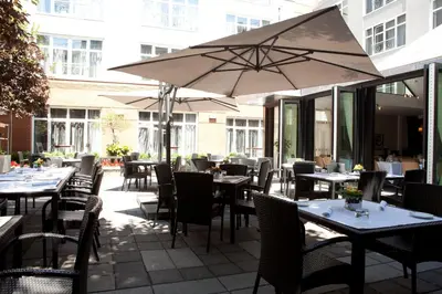 a restaurant with tables and chairs and an umbrella at Hôtel Saint-Sulpice in Montréal