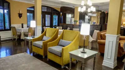 a lobby with yellow chairs and a table at Le St-Martin Hotel & Suites in Laval