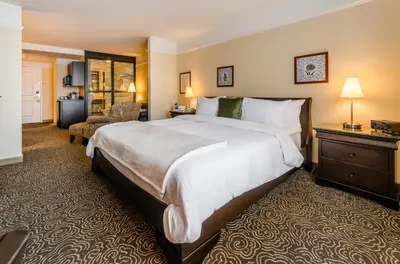a hotel room with a large bed and a chair at Le St-Martin Hotel & Suites in Laval