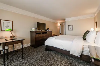 a hotel room with a bed and a desk and a television at Le St-Martin Hotel & Suites in Laval