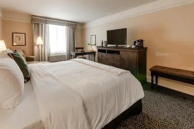 a hotel room with a bed and a television at Le St-Martin Hotel & Suites in Laval
