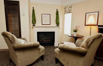 a living room with two chairs and a fireplace at Le St-Martin Hotel & Suites in Laval