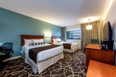 a hotel room with two beds and a television at Hotel Universel Montréal in Montréal