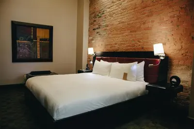 a bedroom with a large bed with a brick wall at Hotel Place D'Armes in Montréal