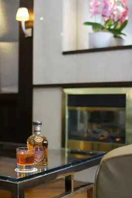 a bottle of whiskey and a glass on a table at Hôtel Le Cantlie Suites in Montréal