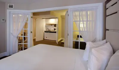 a bedroom with a white bed with white curtains at Hôtel Le Cantlie Suites in Montréal