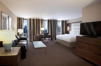 a hotel room with a bed and a flat screen tv at Hôtel Le Cantlie Suites in Montréal