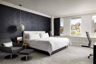 a bedroom with a bed and a desk and a chair at SENS Høtel in Montréal