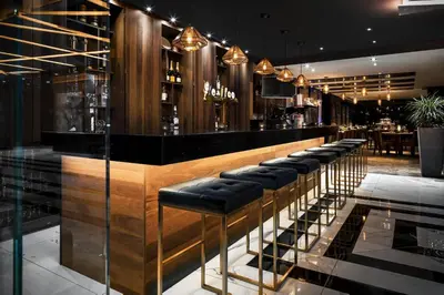 a bar with a row of black stools at SENS Høtel in Montréal