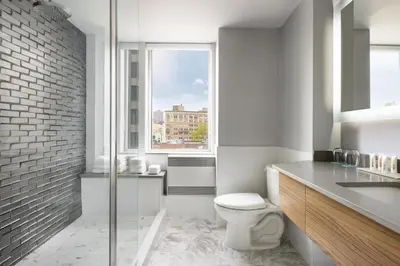 a white bathroom with a toilet and a window at SENS Høtel in Montréal