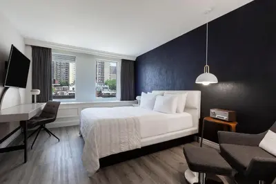 a bedroom with a white bed and a desk and a window at SENS Høtel in Montréal