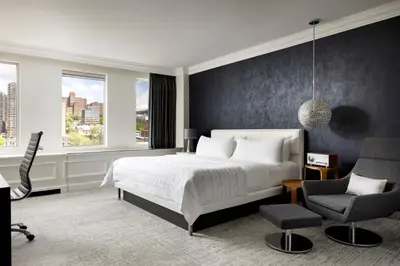 a bedroom with a bed and a desk and a chair at SENS Høtel in Montréal