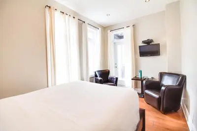 a bedroom with two chairs and a bed and a tv at hotel & spa Carré Saint-Louis in Montréal