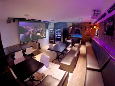 a restaurant with tables and chairs and a large screen at M Montreal Hostel in Montréal