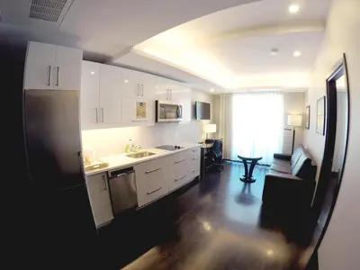 a kitchen with white cabinets and a black refrigerator at M Montreal Hostel in Montréal