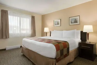 a hotel room with a large bed and a window at Days Inn by Wyndham Montreal East in Montréal
