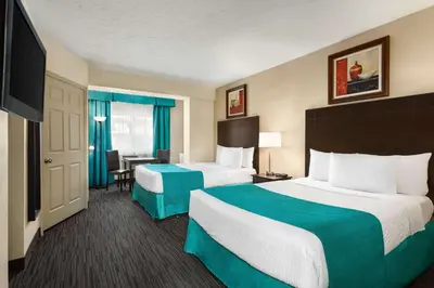 a hotel room with two beds and a television at Days Inn by Wyndham Montreal East in Montréal