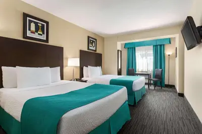 a hotel room with two beds and a desk at Days Inn by Wyndham Montreal East in Montréal