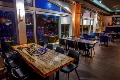 a restaurant with a wooden table and chairs at Hôtel Château Joliette in Joliette