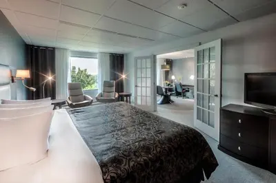 a hotel room with a bed and a flat screen tv at Hôtel Château Joliette in Joliette