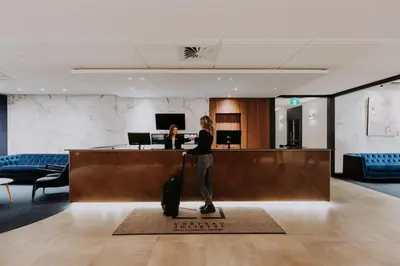 a person with a suitcase standing at a hotel lobby at Hôtel Château Joliette in Joliette