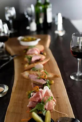 a wooden cutting board with meat and a glass of wine at Hôtel Château Joliette in Joliette