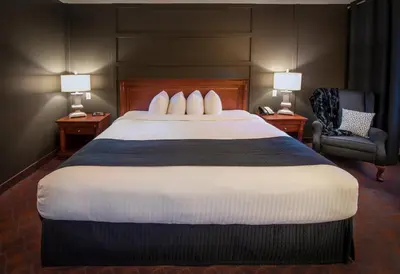 a hotel room with a large bed and a chair at Hôtel Château Joliette in Joliette