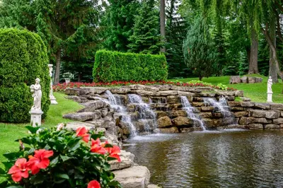 a waterfall in a garden with red flowers at Chateau Vaudreuil in Vaudreuil-Dorion