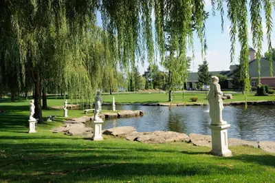 a park with statues in front of a pond at Chateau Vaudreuil in Vaudreuil-Dorion