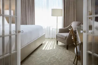 a bedroom with a bed and a chair and a window at Chateau Vaudreuil in Vaudreuil-Dorion