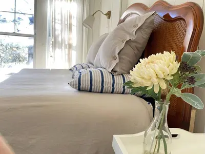 a vase of flowers on a table next to a bed at Family Winter Home in the Eastern Townships in Ayer's Cliff