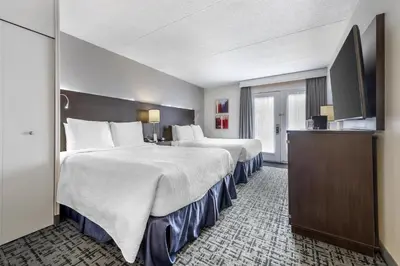 a hotel room with two beds and a television at Best Western Hotel Brossard in Brossard