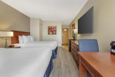 a hotel room with two beds and a desk at Best Western Hotel Brossard in Brossard