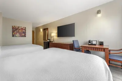 a hotel room with two beds and a desk and a tv at Best Western Hotel Brossard in Brossard
