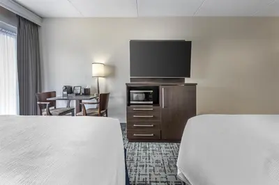 a hotel room with two beds and a flat screen tv at Best Western Hotel Brossard in Brossard
