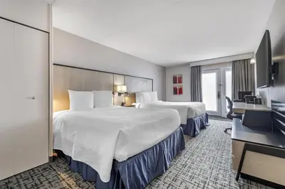 a hotel room with two beds and a flat screen tv at Best Western Hotel Brossard in Brossard