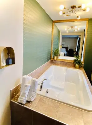a bathroom with a tub with towels and a mirror at Hotel Dorion in Montréal