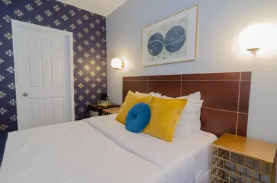 a bedroom with a bed with yellow and blue pillows at Hotel Dorion in Montréal