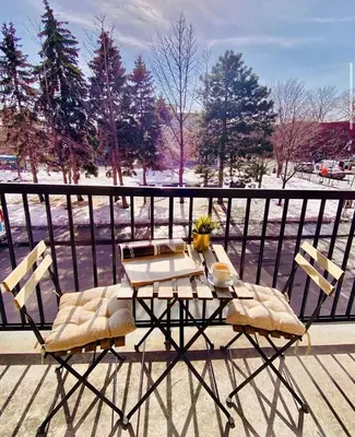 a table and two chairs on a balcony with snow at Hotel Dorion in Montréal