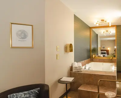 a bathroom with a tub and a large mirror at Hotel Dorion in Montréal