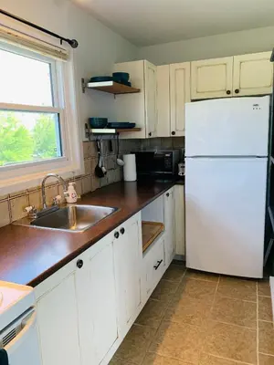 a kitchen with a white refrigerator and a sink at Le Philémon Club Azur plage Memphrémagog in Magog-Orford