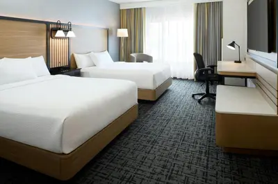 a hotel room with two beds and a desk at Fairfield Inn & Suites by Marriott Montreal Airport in Dorval