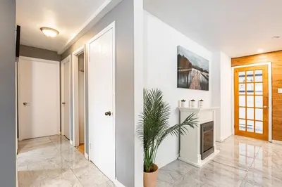 a hallway with white walls and a fireplace and a plant at Chez Joe - CITQ #3I74I4 in Terrebonne