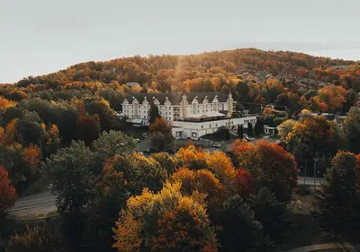 a large building on top of a hill with trees at Hotel Chateau Bromont in Bromont
